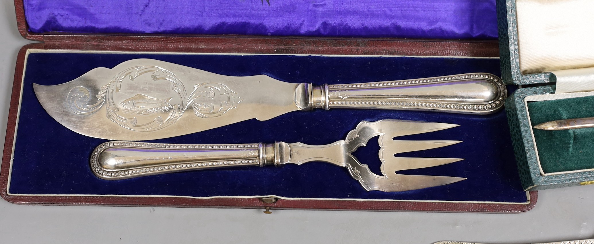 A late Victorian engraved silver christening trio, Wakely & Wheeler, London, 1889/90, a cased novelty silver letter opener, with fish handle, C.J. Vander Ltd, London, 1971 and a cased pair of silver plated fish servers.